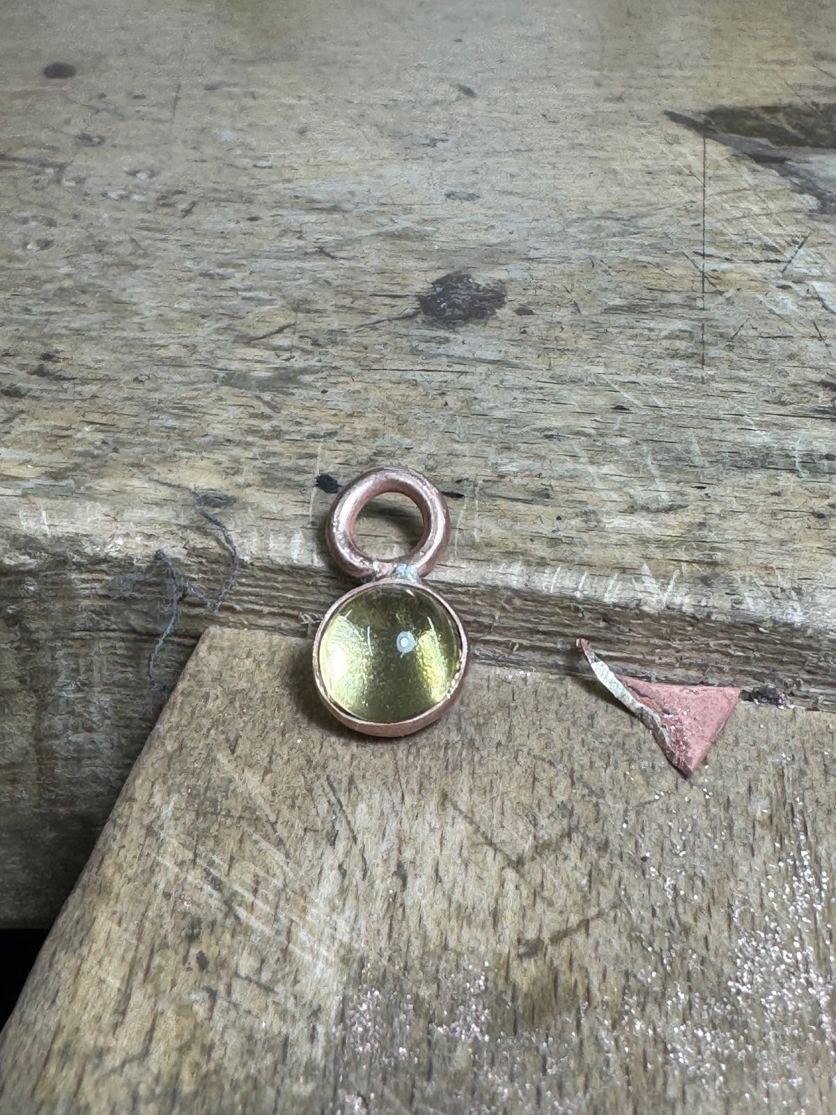 Glass cabochon set over gold leaf, framed in copper