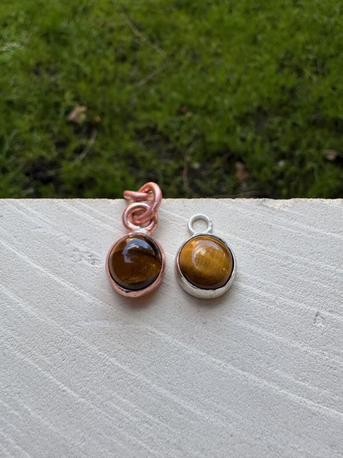 Two tiger's eye pendants, one set in copper and one in silver